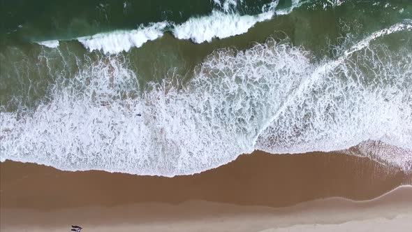 Shot looking down at waves crashing onto the beach
