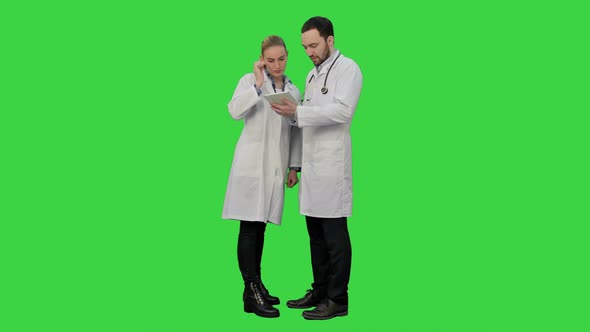 Pretty Female Nurse and Handsome Doctor with Stethoscope Using Digital Tablet on a Green Screen