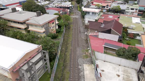 Aerial shot flying over train tracks and houses in San Jose, Costa Rica