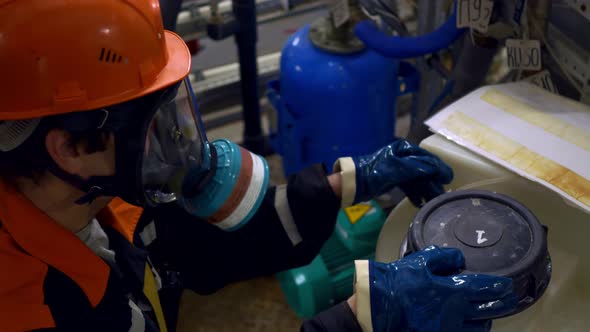 A Laboratory Assistant in the Chemical Industry in Overalls a Gas Mask and a Work Helmet Opens a