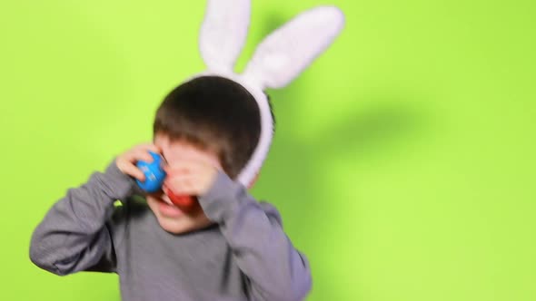 Cheerful Happy Boy with Bunny Ears on Head is Playing with Easter Colorful Eggs