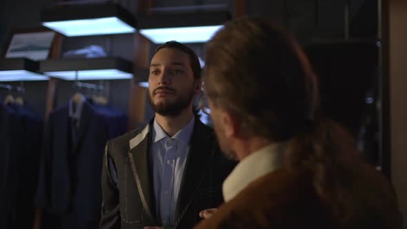 Bearded Elegant Businessman Stand Still in Tailoring Atelier As Old Tailor Measure Jacket on Man