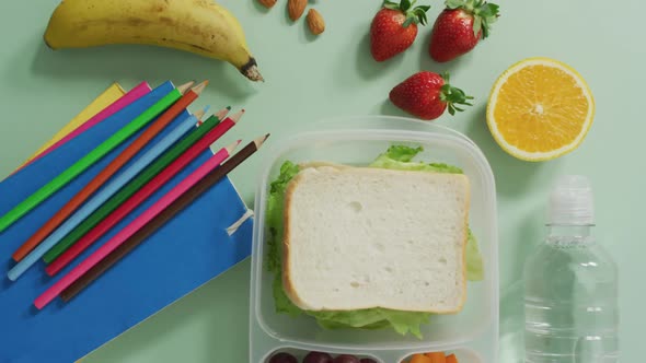 Video of healthy packed lunch of fruit and vegetables, with coloured pencils and notebooks