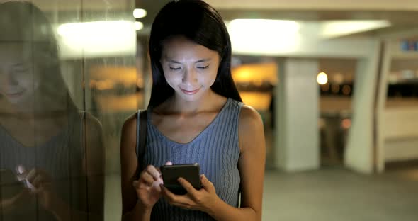 Woman working on smart  phone in the city at night 