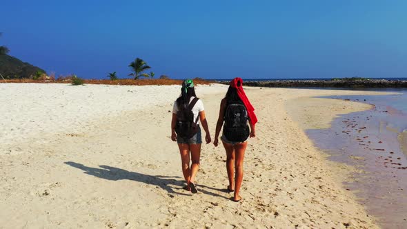 Ladies together enjoying life on perfect tourist beach trip by blue water with white sandy backgroun