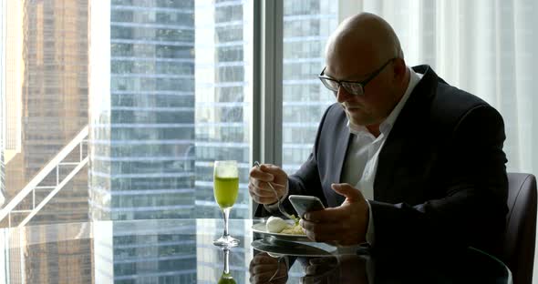 Businessman in A Suit, He Sits in His Office's Panoramic Window in Which You Can See High-Rise