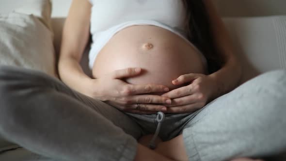 Close-up of Pregnant Woman's Belly and Baby Kicks While Mother Stroking and Touching Belly