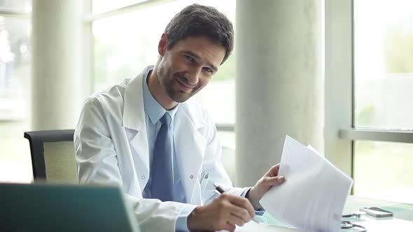 Doctor doing paperwork and smiling at camera