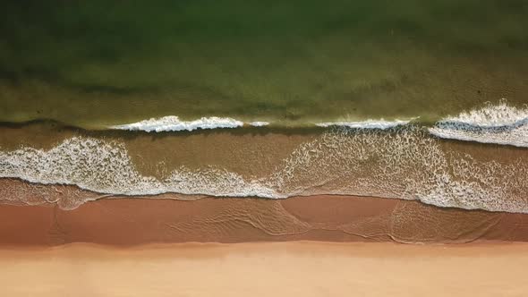 Drone View of Sea Foam Waves, Beating Against Sandy Seashore.