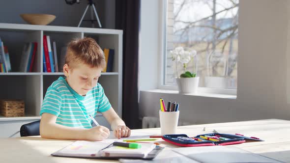 Boy is Doing  Homework at the Table. Cute Child is Learning at Home.