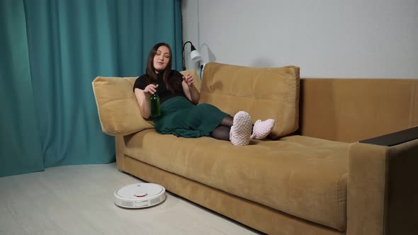 Robot Vacuum Cleaner Delivers Alcohol to Woman Sitting on Sofa