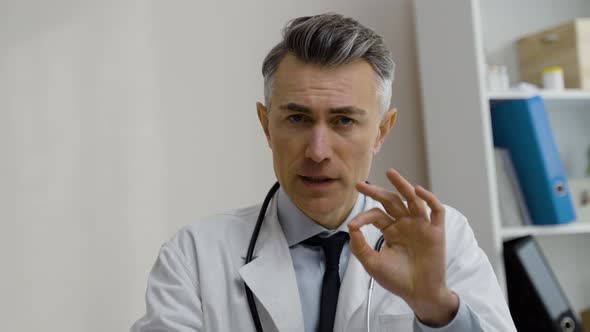 Doctor looks at camera and talking on the distance. Confident caucasian male MD