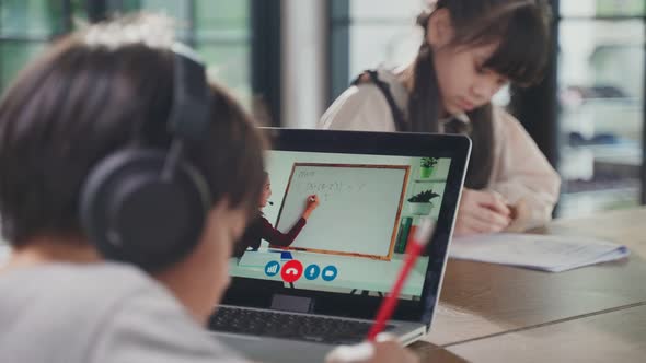 Asian little young boy and girl learning online class from school teacher by digital remote internet