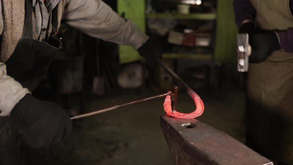 Two Blacksmiths Are Forging Iron Horseshoe in a Forge, Close-up