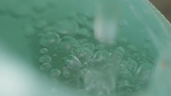 Water dripping into a green bucket in slow motion