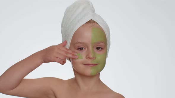 Beautiful Smiling Child Girl Kid in Towel on Head Applying Cleansing Moisturizing Green Facial Mask