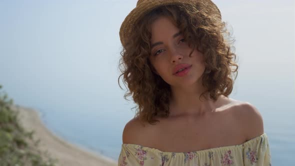 Curly Woman Looking Camera with Serene Smile in Front Ocean Closeup