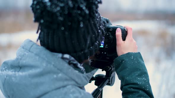 Close-up of the hands of a girl who takes pictures in the winter forest