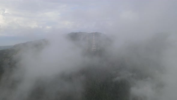 Aerial view fly over low cloud toward telecommunication tower