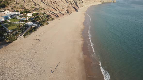 One person alone walking on the sand beach, Praia da Luz, Algarve. Solitude and holidays concept