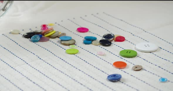 Colorful Buttons Falling on Striped Fabric Closeup