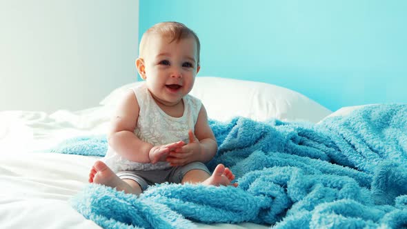 Playful baby girl sitting on bed