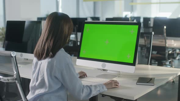 Business Multiethnic Woman Working on Desktop Computer with Green Screen Mock Up Display in Busy