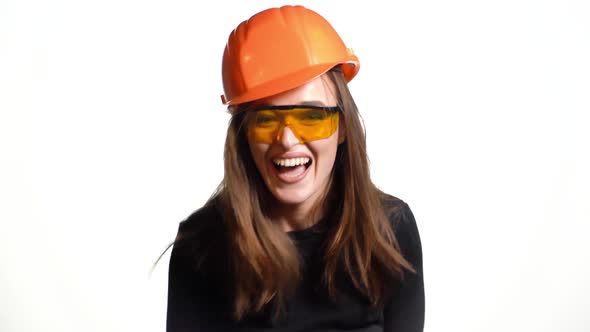 Cheerful girl engineer in black jumper and a bright helmet emotionally talks about business