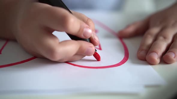 Child Draws Hearts on Paper with Pink Markers