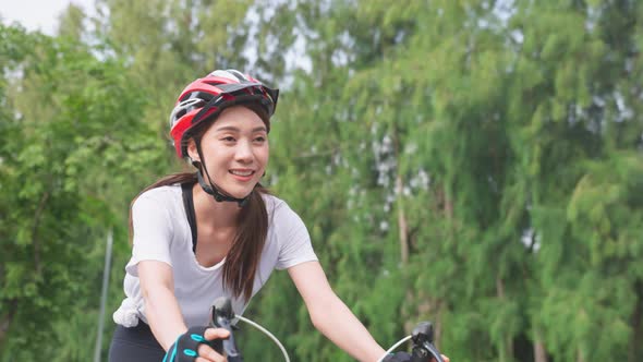 Asian young sport woman in sportswear wear helmet riding bicycle in the evening in public park.