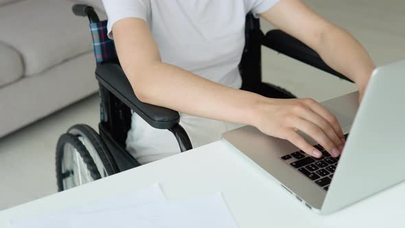 Female Student Learning Online Using Laptop Typing Sitting in Wheelchair in Apartment Busy with