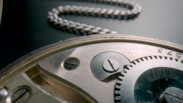 Silver Chain and Internal Working Mechanism of an Antique Pocket Watch on a Gray Background