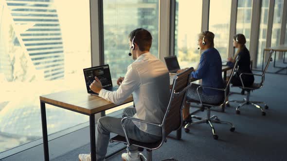 Back View of Handsome Young Businessman and Beautiful Business Women in Headsets Working in Office