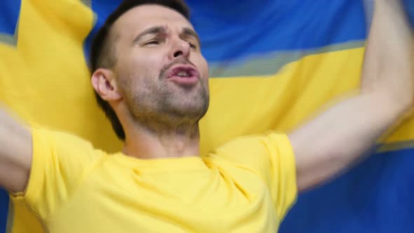 Swedish Fan Celebrating While Holding the Flag of Sweden