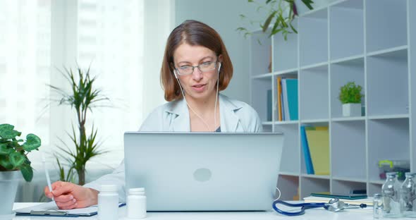 A friendly female medic on video communication is talking online with a client. 4K