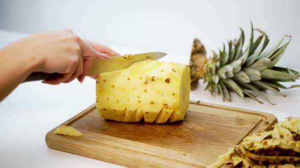 Hands slicing pineapple. Person slicing ripe pineapple with knife on table