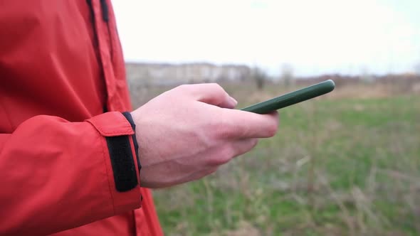 A Man Uses a Smartphone Surf the Internet on the Street