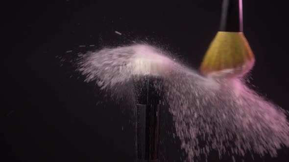 Two Makeup Brushes with Powder on a Dark Background