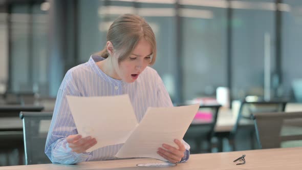 Young Woman Upset While Reading Documents in Office