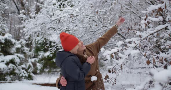 In A Snow Covered Park, A Boy And His Mother Have Fun Together