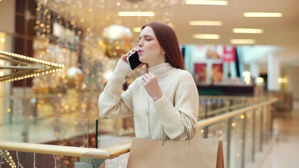 Happy Excited Young Woman Talking Using Mobile Phone Standing in Corridor of Shopping Mall with