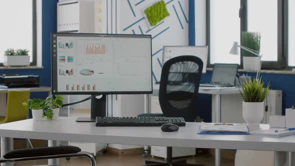 Computer in Empty Workplace with Graphs on Screen and Wheelchair