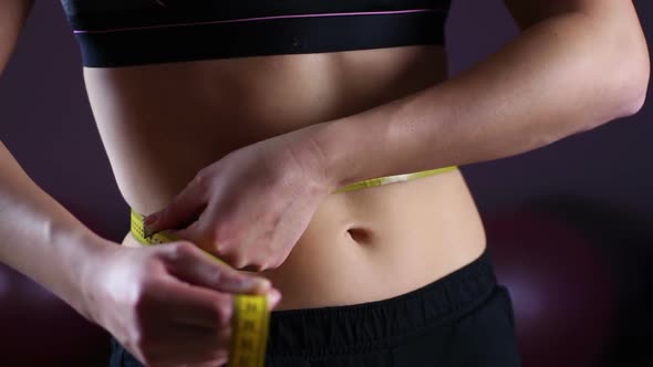 Female Flat Belly Closeup, Woman Using Measuring Tape to Show Weightloss Result