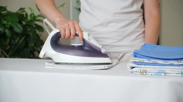 A Woman Irons a Baby Diaper with an Iron on an Ironing Board Closeup