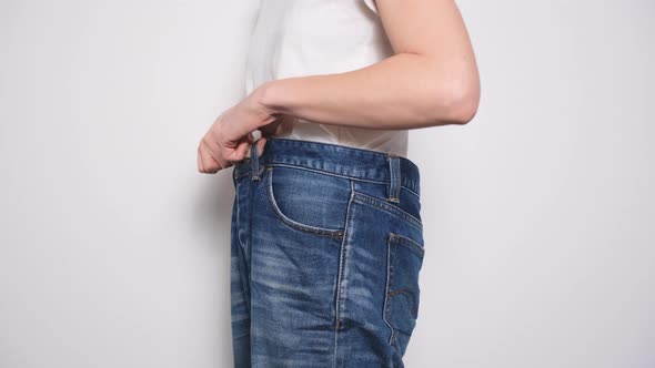 Happy Woman Dancing in Oversized Jeans on White Background