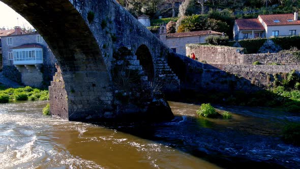 Aerial View Of Stone Arches Of Bridge of Ponte Maceira Over The River Tambre. Dolly Shot