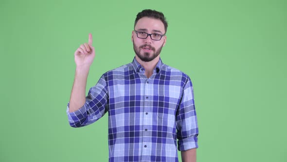 Happy Young Bearded Hipster Man Talking While Pointing Up