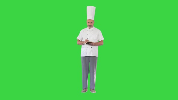 Senior Male Chef Takes Notes on a Green Screen Chroma Key