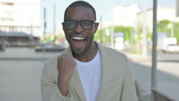 Portrait of Excited African Man Celebrating Success Outdoor