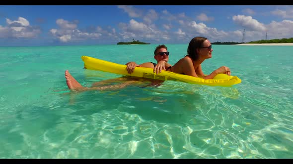 Teenage lovers sunbathe on perfect bay beach trip by blue water with white sand background of the Ma